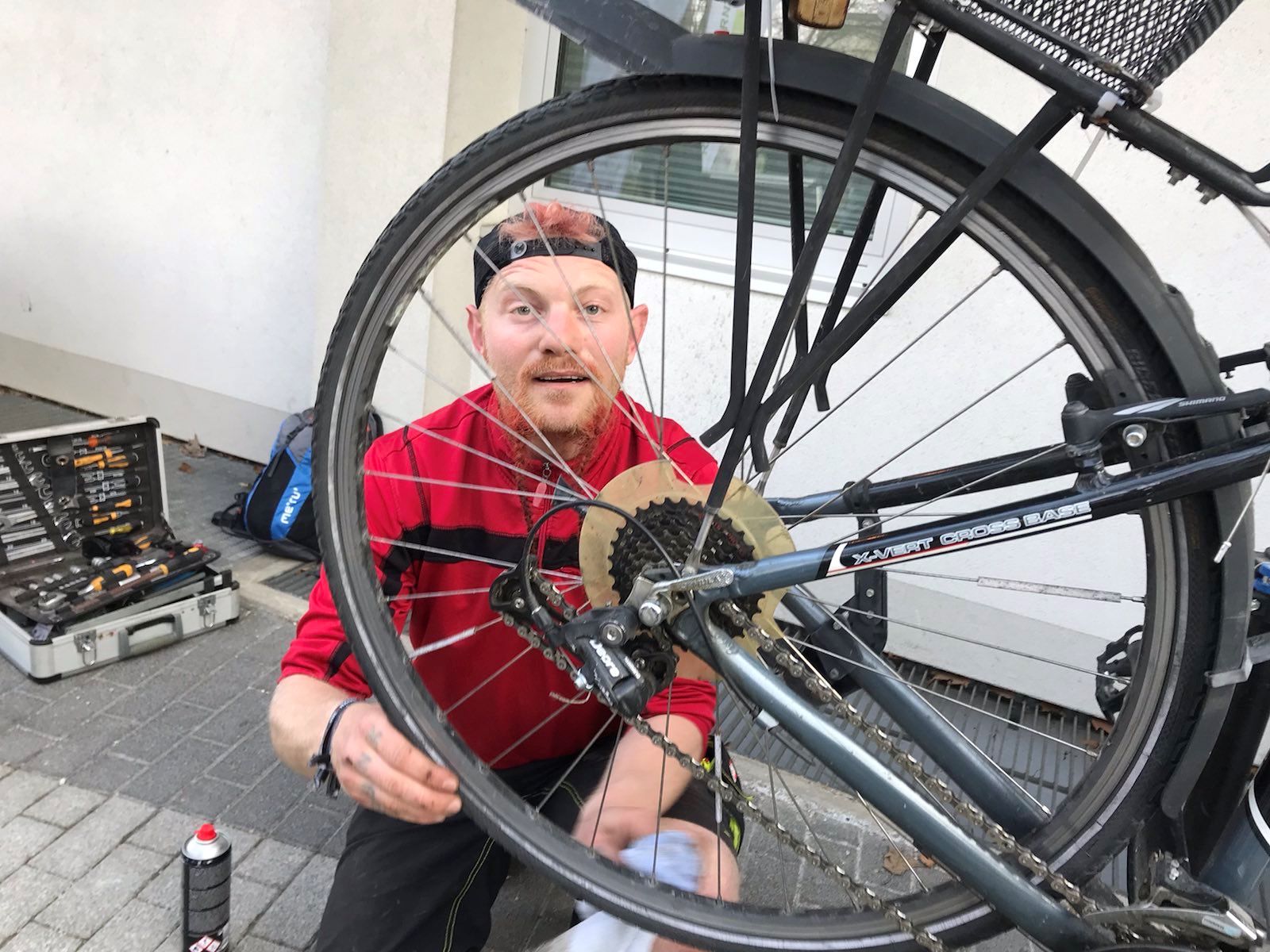 Mann in rotem T-Shirt  wechselt schadhaften Fahrradreifen im Rahmen des Repair Cafes Viktring