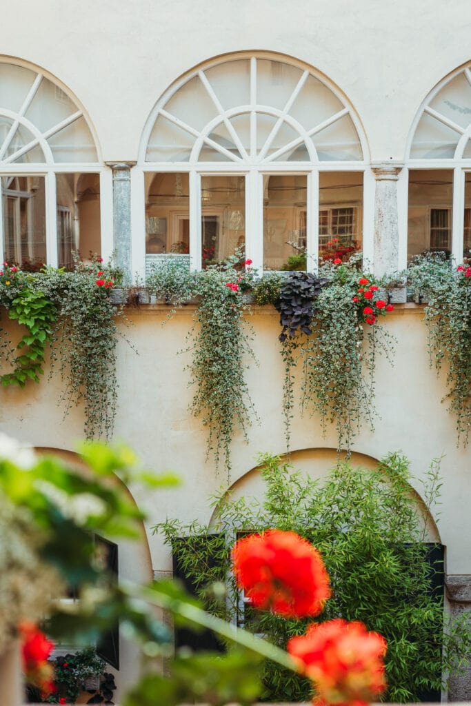 bezaubernder Innenhof mit halbrunden Fenstern und Blumen am Fensterbrett 