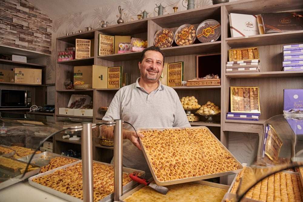 Mann in syrischer Bäckerei Klagenfurt
Damascino zeigt Blech mit frischen Keksen