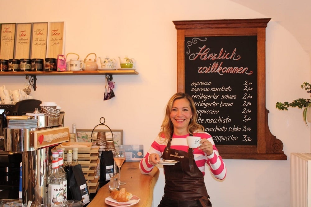 Kellnerin in der Kaffeewerkstadt beim Cappuccino Trinken an der Theke 