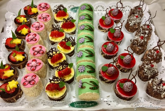 ein Tablett mit kleinen, hausgemachten Kuchen der Konditorei Farnberger aus Klagenfurt. Sie sind bunt verziert mit Fruchtspiegel, Schokolade, Beeren und Marzipan in verschiedenen Farben