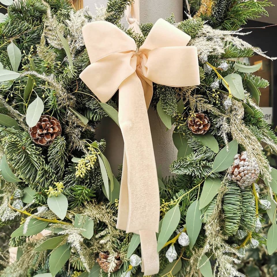 Weihnachtslicher Türkranz mit weißer Schlaufe aus dem Blumenladen Blumen Pucher in Klagenfurt 