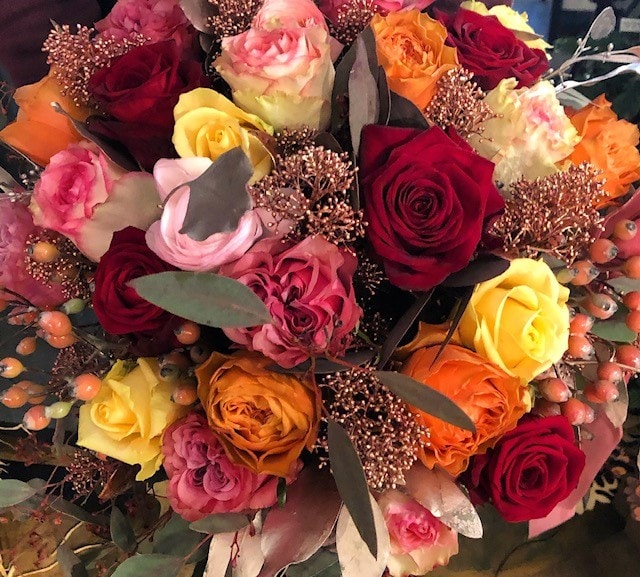 Blumenkranz von Blumen Pucher aus Klagenfurt mit Rosen in rot, orange, gelb und rosa und Blättern als Weihnachtsdekoration