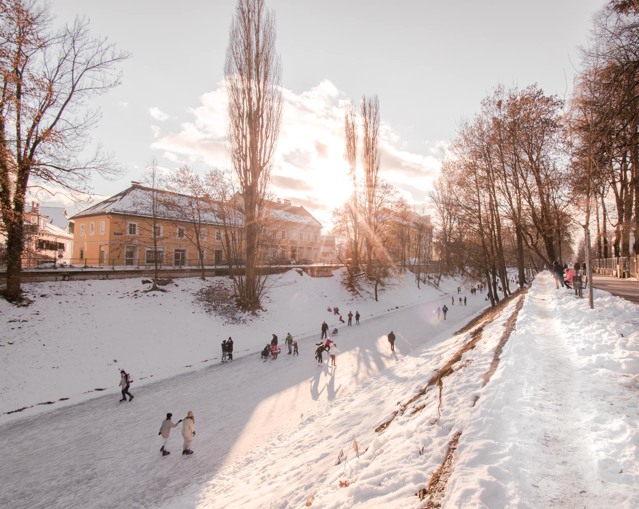 Menschen beim Eislaufen an sonnigem Wintertag auf der Lend in Klagenfurt