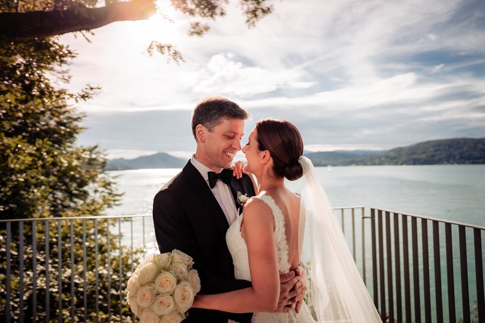 ein glückliches Brautpaar im Park des Schloss Loretto in Klagenfurt, im Hintergrund der Wörthersee
