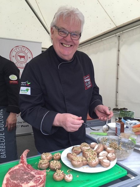 Koch vom Vitalgarten bereitet Champignons zu und lächelt in die Kamera