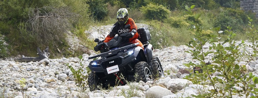 ein Mann fährt mit einem Quad und Schutzkleidung durch ein trcckenes Bachbett