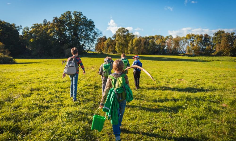 Freiluft Workshop bei Erlebensraum Natur, die Teilnehmer gehen mit Rucksack über eine Wiese