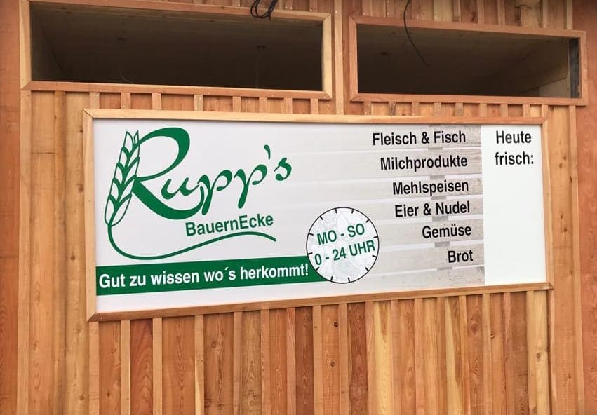 Außennansicht des 24h Verkaufadens Rupps Bauernecke mit der Aufschrift, welche Produkte es zu Kaufen gibt: Fleisch & Fisch, Milchprodukte, Mehlspeisen, Eier & Nudel, Gemüse und Brot