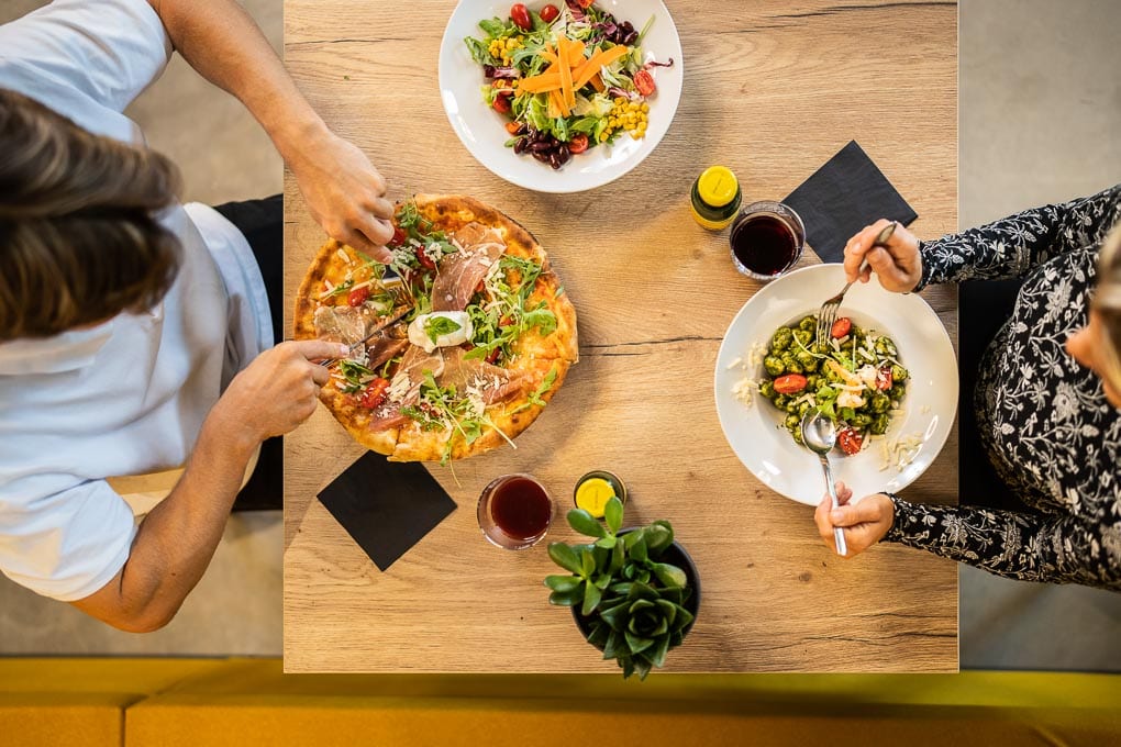 2 Personen essen Pizza, Gnocchi mit Pesto und Salat im Restaurant des JUMPWORLD.ONE in Klagenfurt