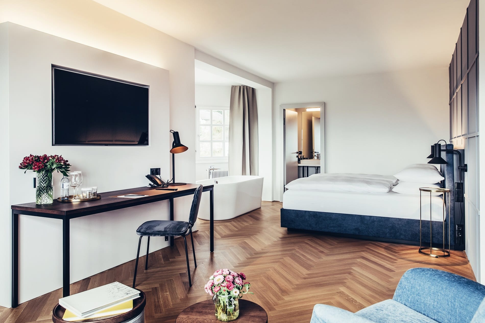 Suite mit großem Doppelbett und freistehender Badewanne im Hotel Dermuth in Klagenfurt