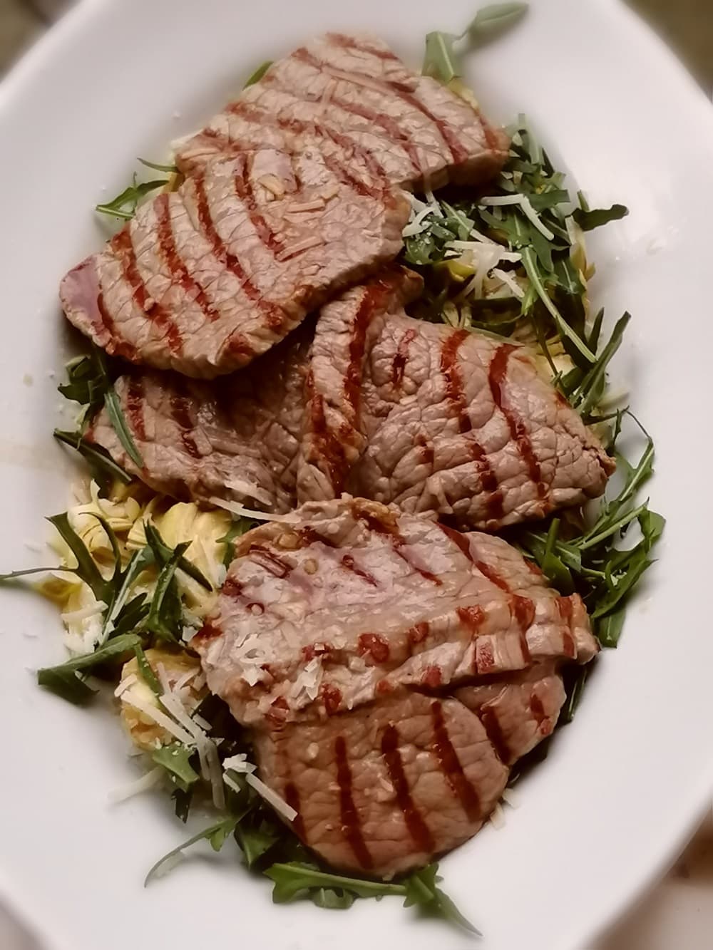 ein Teller mit Artischocken, Rucola und gegrilltem Bistecca