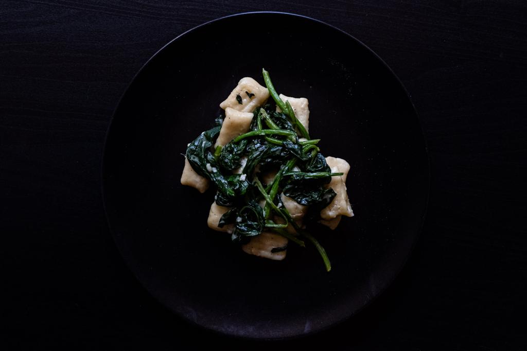 Gnocchi mit Gorgonzola und Spinat auf einem schwarzen Teller angerichtet