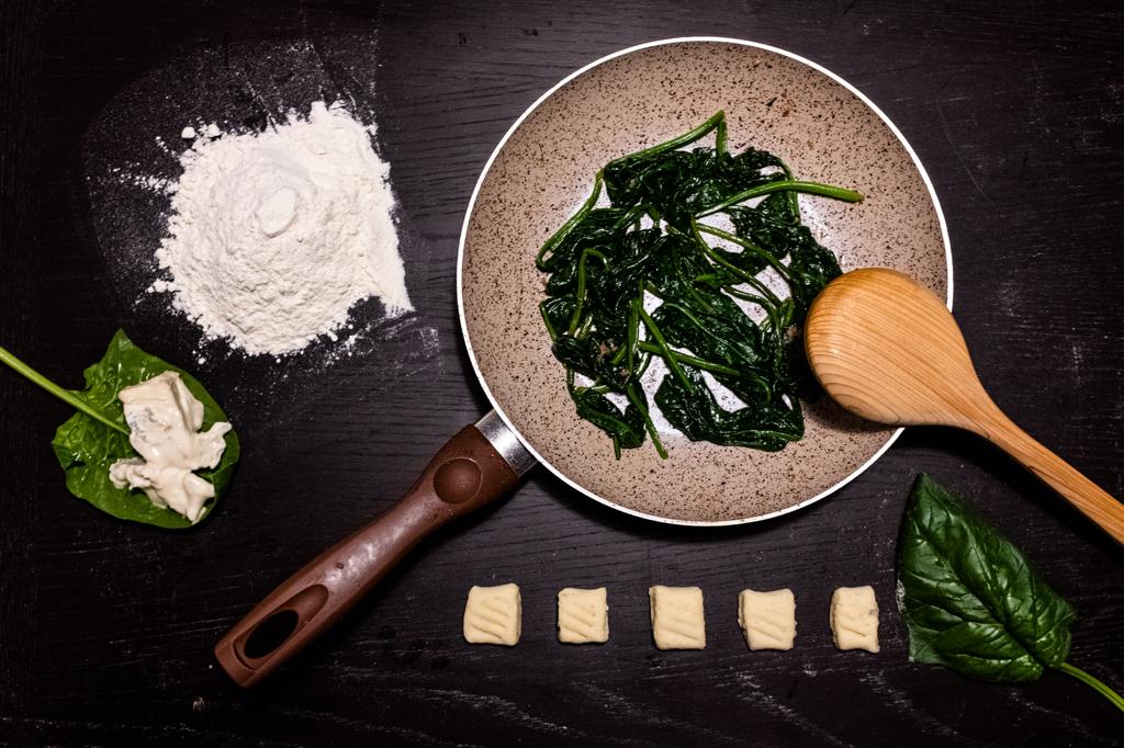 Rezepttipp für die Winterküche: Gnocchi mit Gorgonzola und Spinat in einer Pfanne mit einem Kochlöffel
