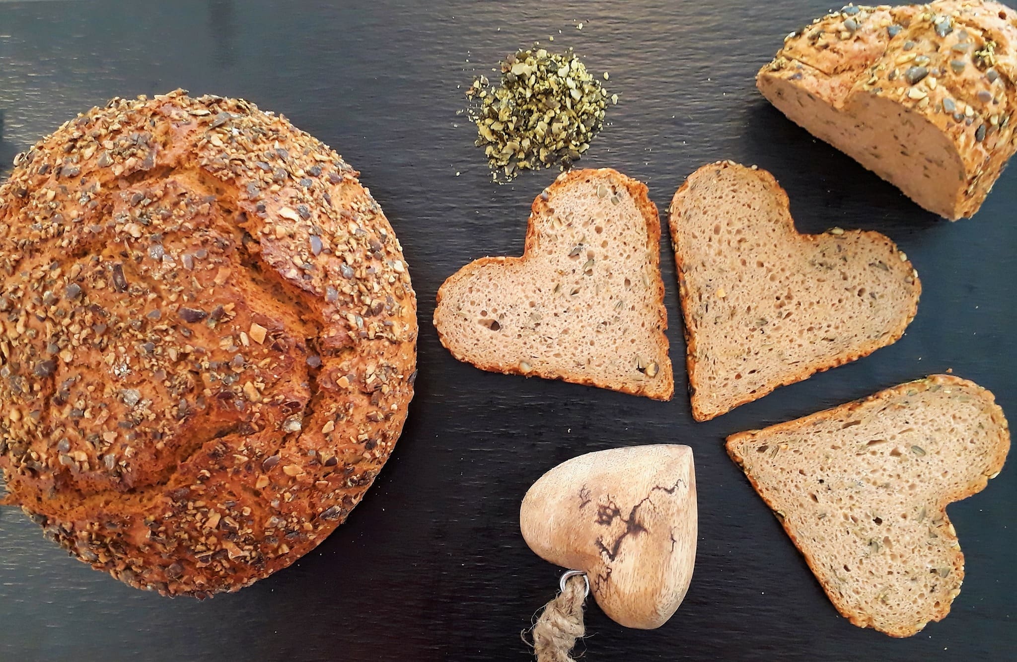 Kürbisbrot von der Bäckerei Stocklauser in Klagenfurt auf einer schwarzen Schiefertafel angerichtet, der kleine Laib ist in einer Form gebacken, die beim Aufschneiden Herzformen macht