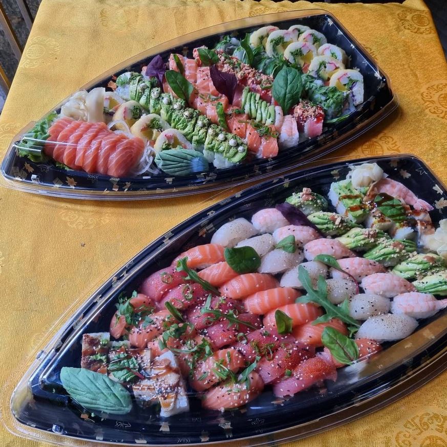 verschiedene Sorten Sushi von Kyo Kitchen und Bar als Take Away auf Tellern mit Schiffform angerichtet, es gibt Lachs, Thunfisch, Butterfisch, Krabbe, Avocado