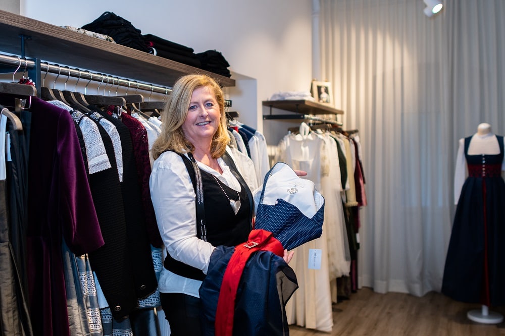 Ulli Seebacher in ihrem Atelier Trachencouture Erbstücke in Klagenfurt, sie präsemtiert ein blaues Kärntner Dirndl mit roter Schürze und weißer Bluse