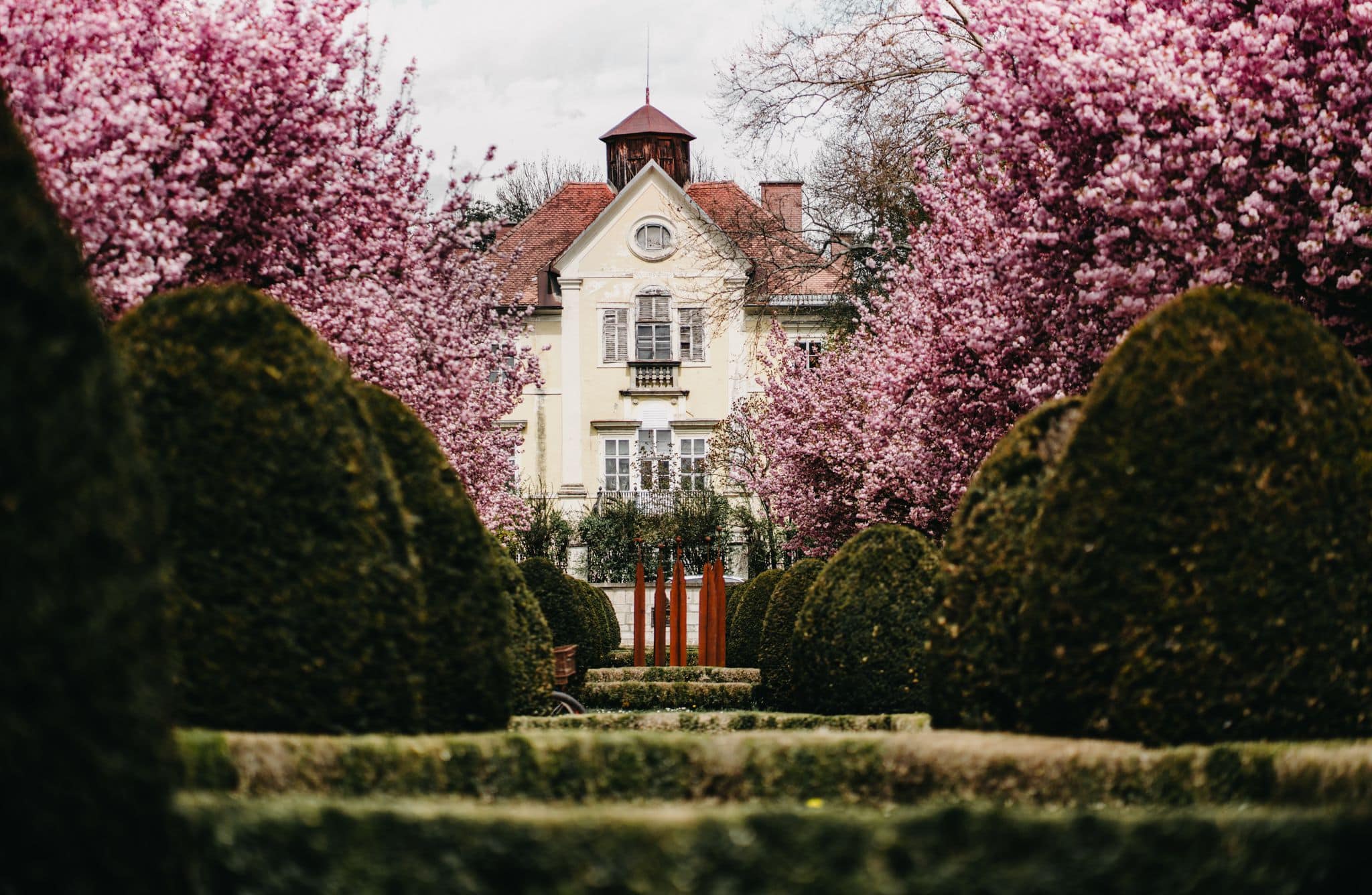 Schloss in Klagenfurt umgeben von blühenden Bäumen 