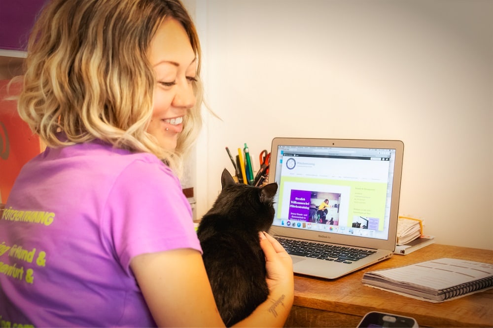 die Tiertrainerin Laura Gentile sitzt mit einer Katze vor dem Laptop
