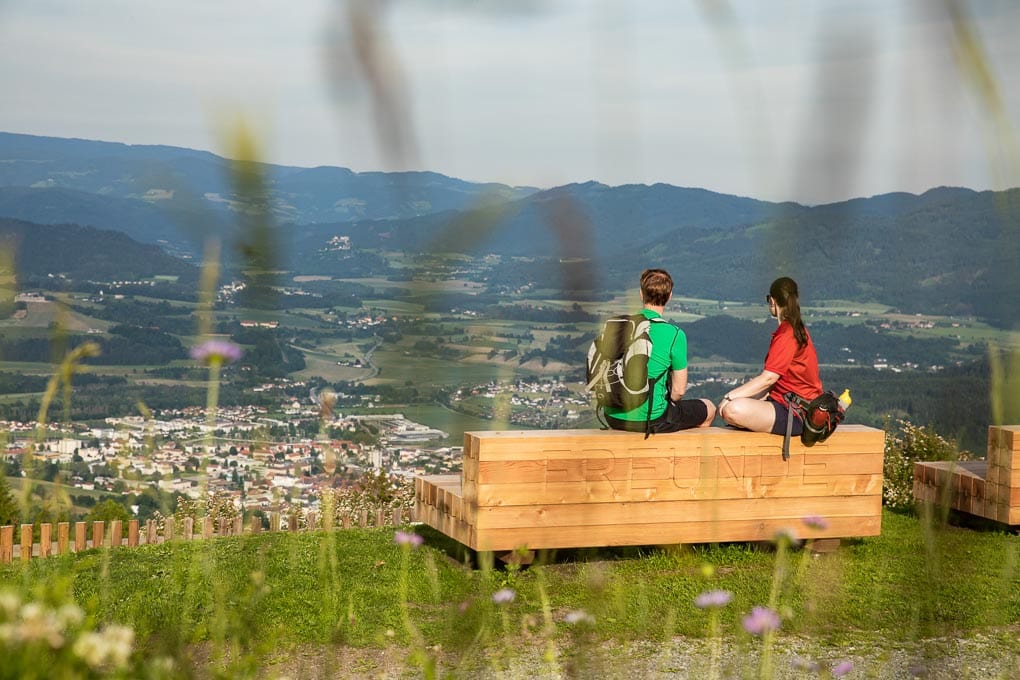 Paar bei kurzer Pause auf einer Holzbank während des Vierbergelaufs in Kärnten