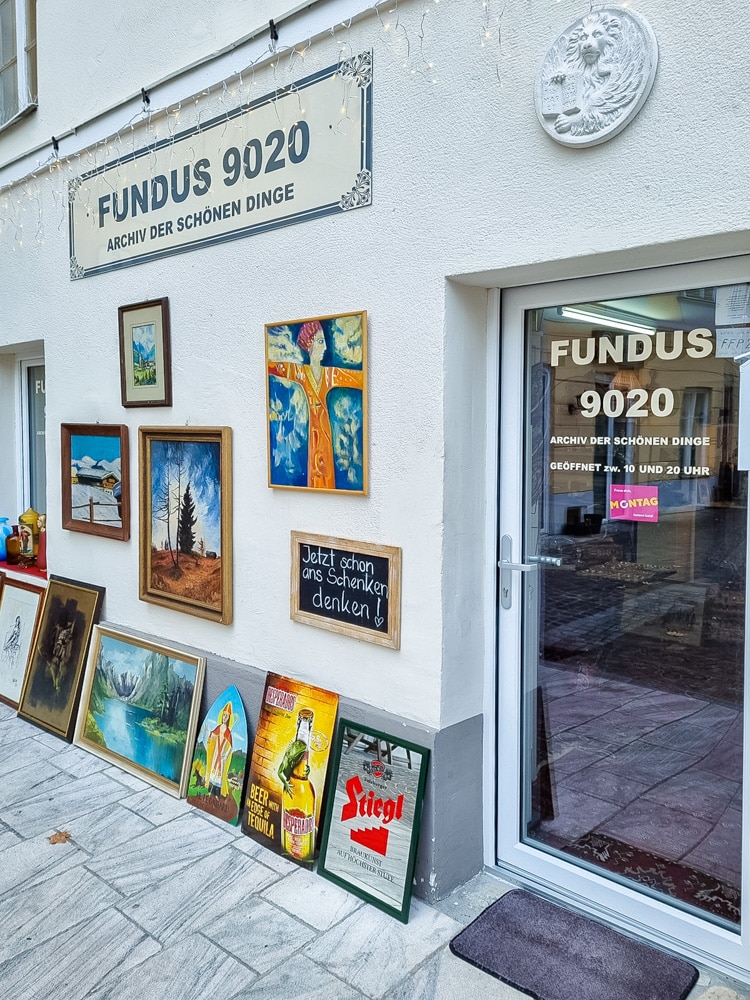 Das Geschäft "Fundus" in der Badgasse - am Bild ist der Eingang zum Geschäft zu sehen, rechts die Glastür mit Geschäftsbeschriftung, über der Tür ein rundes Relief mit einem Löwen, links neben der Tür sind Bilder und Schilder gestellt und gehängt, darüber hängt ein großes Schild mit der Aufschrift "Fundus 9020 Archiv der schönen Dinge"