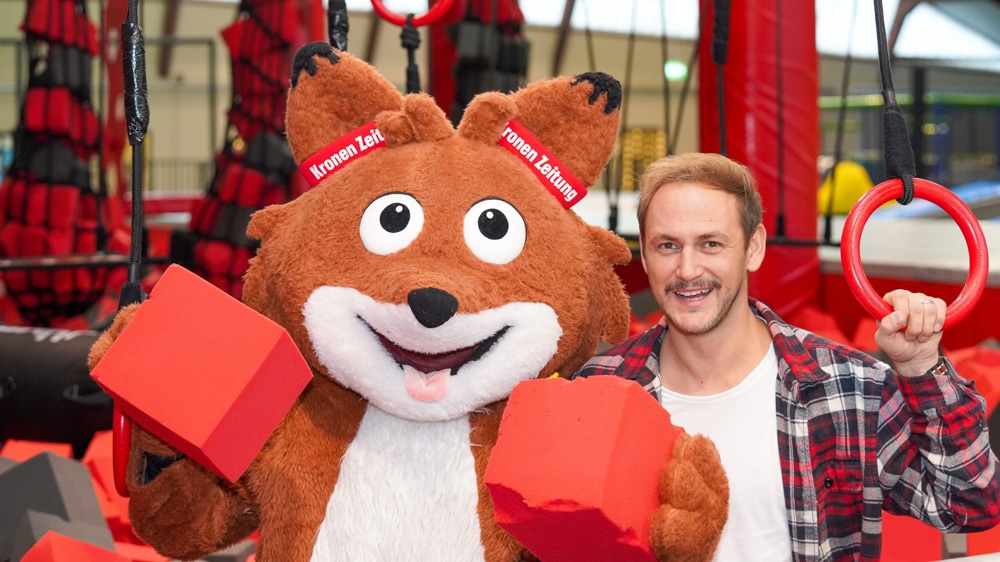 Am Bild ist links Lesefuchs Theo, rechts daneben ist Leseonkel Christian Krall von der Kronen Zeitung, sie lachen in die Kamera, im Hintergrund ist ein Indoor-Parcour