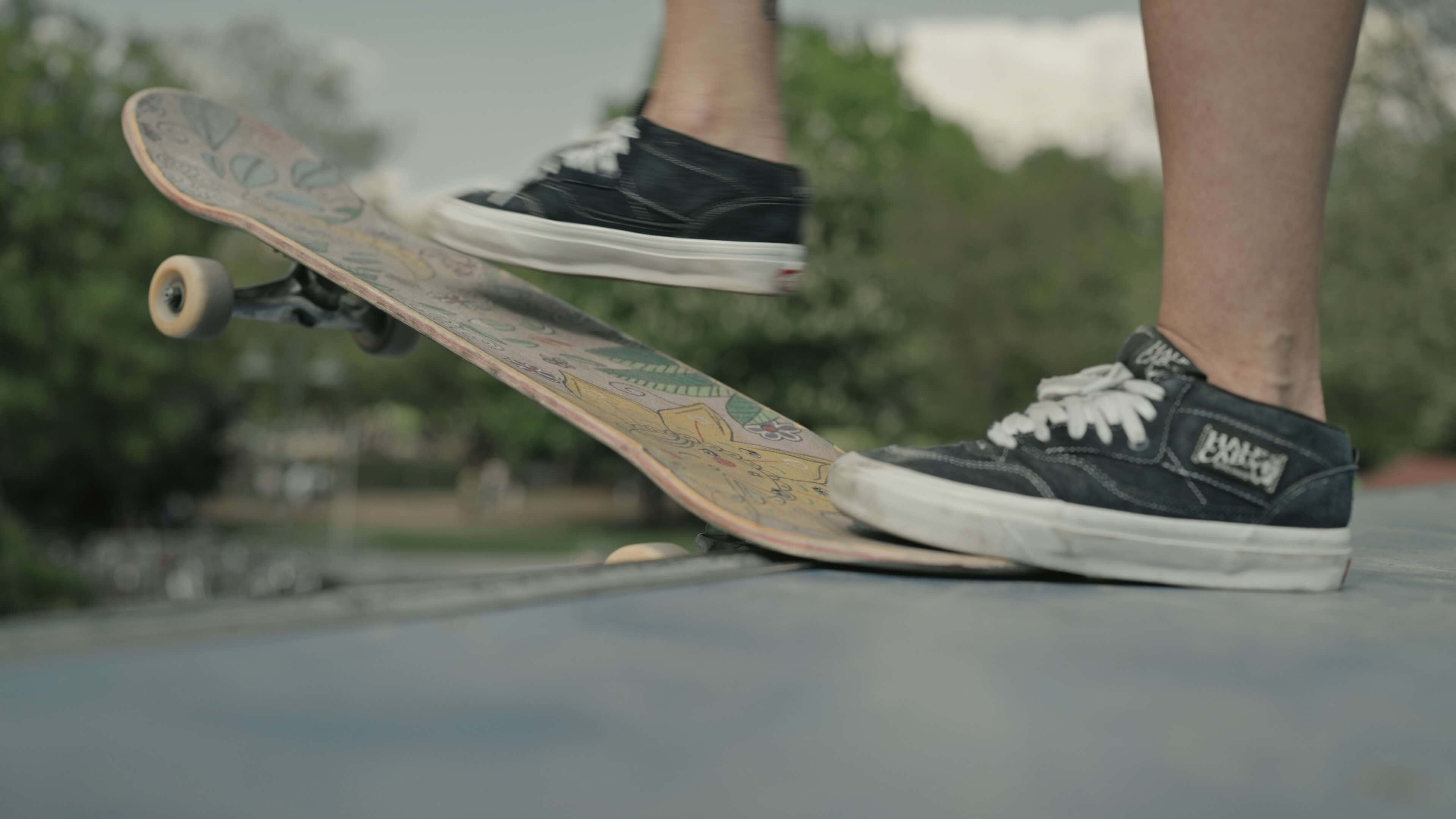 Detail von schwarzen Vans Schuhen und buntem Skateboard