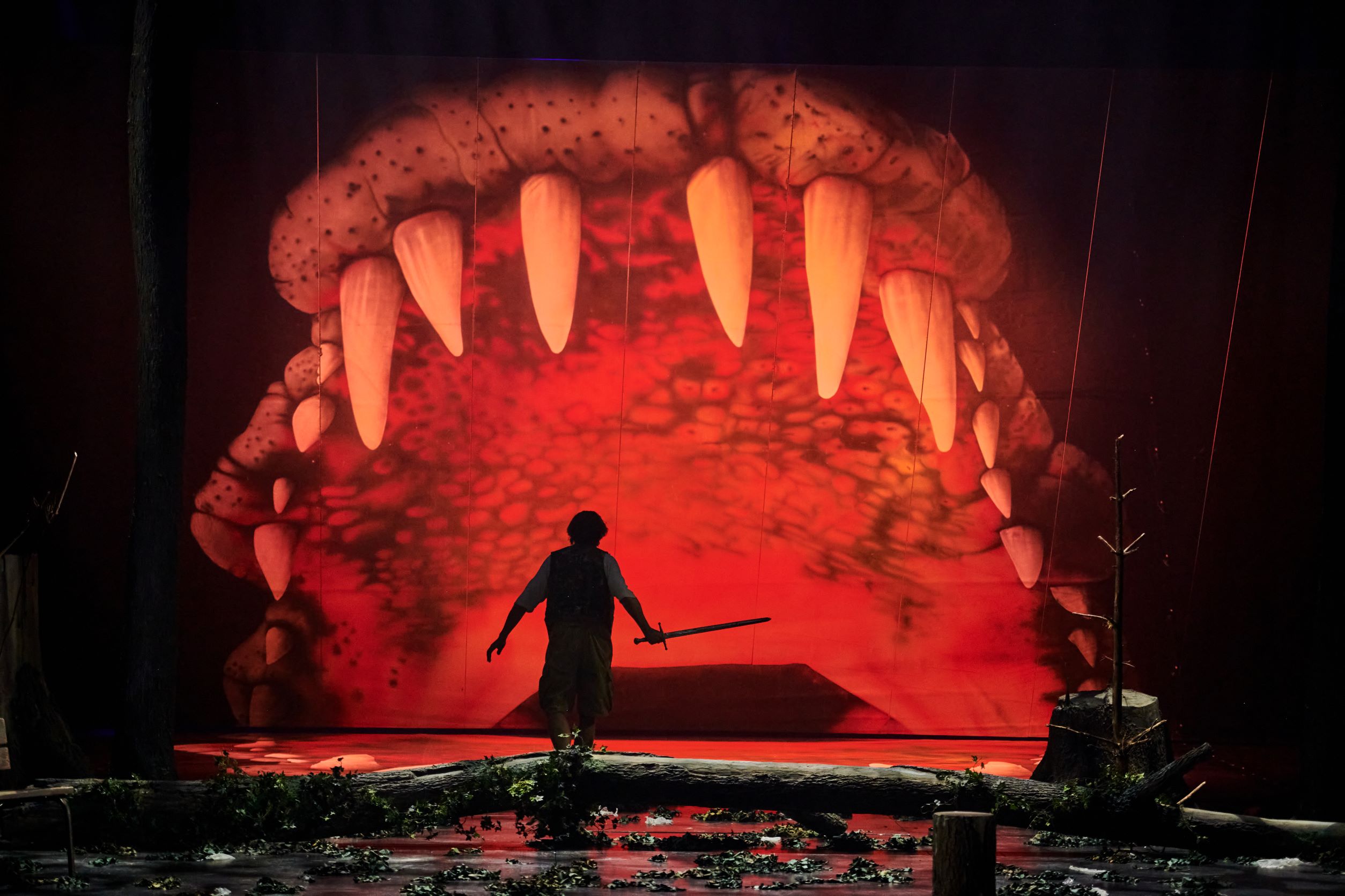 Szenenbild Theater im Stadttheater Klagenfurt. Proganist mit Schwert vor einem Ungeheuer.