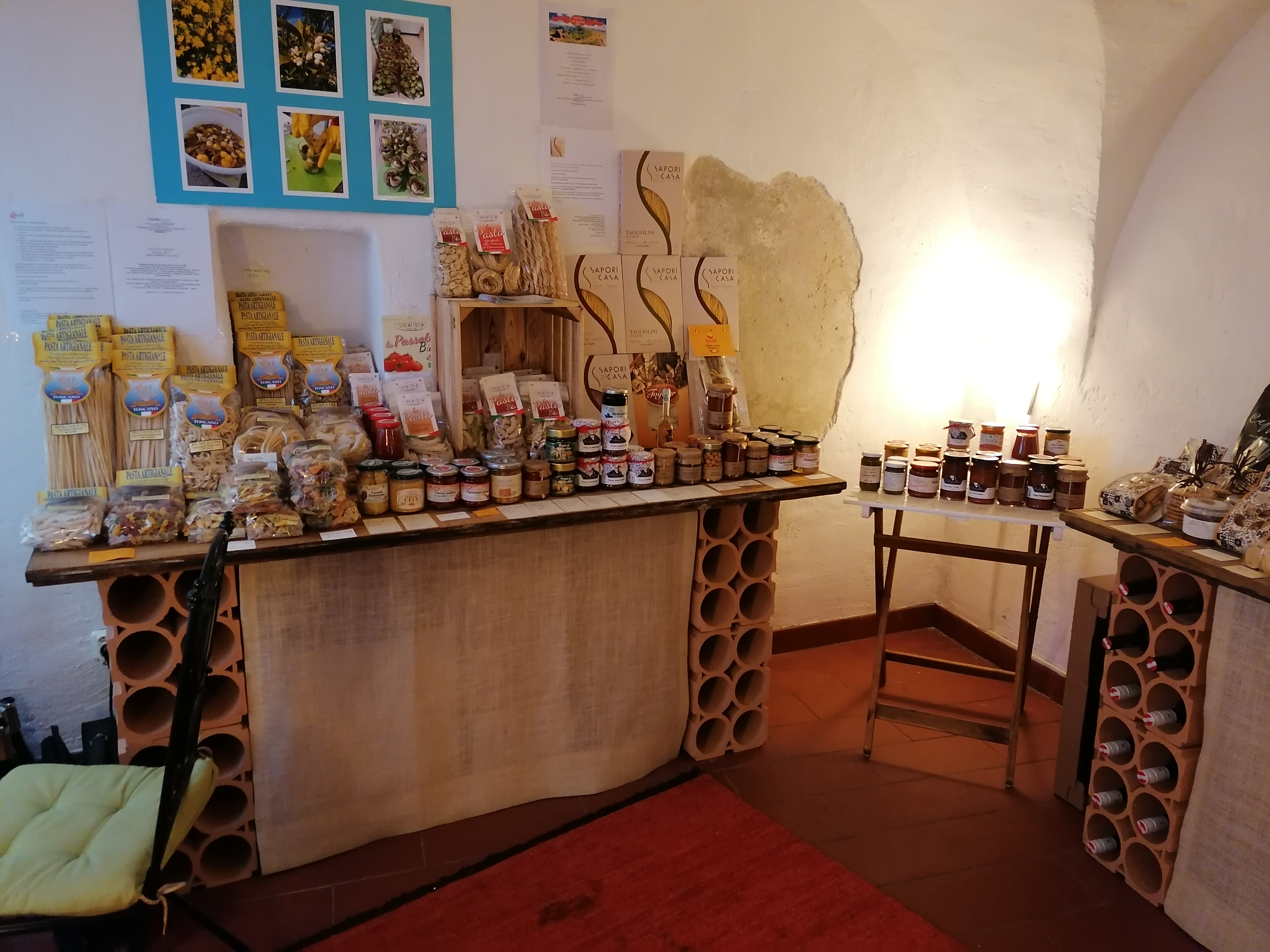 Ein Verkaufsregal im Hofschmankerl mit Produkten wie italienischer Pasta, Sughi, eingelegtem Gemüse und verschiedenen Pesti, am Regal rechts italienisches Feingebäck
