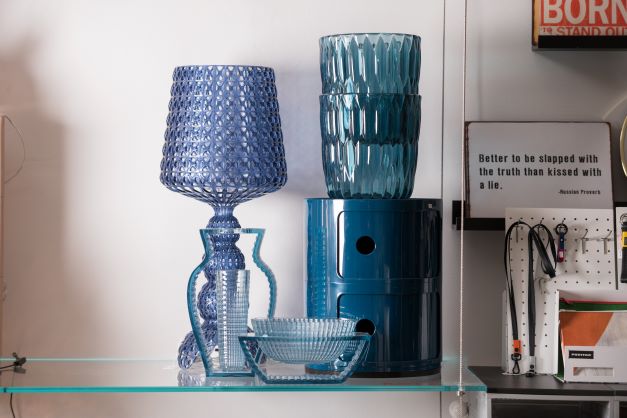 Lampe, Gläser und Aschenbecher in lila bzw. blauem Glas auf einem Glasregal