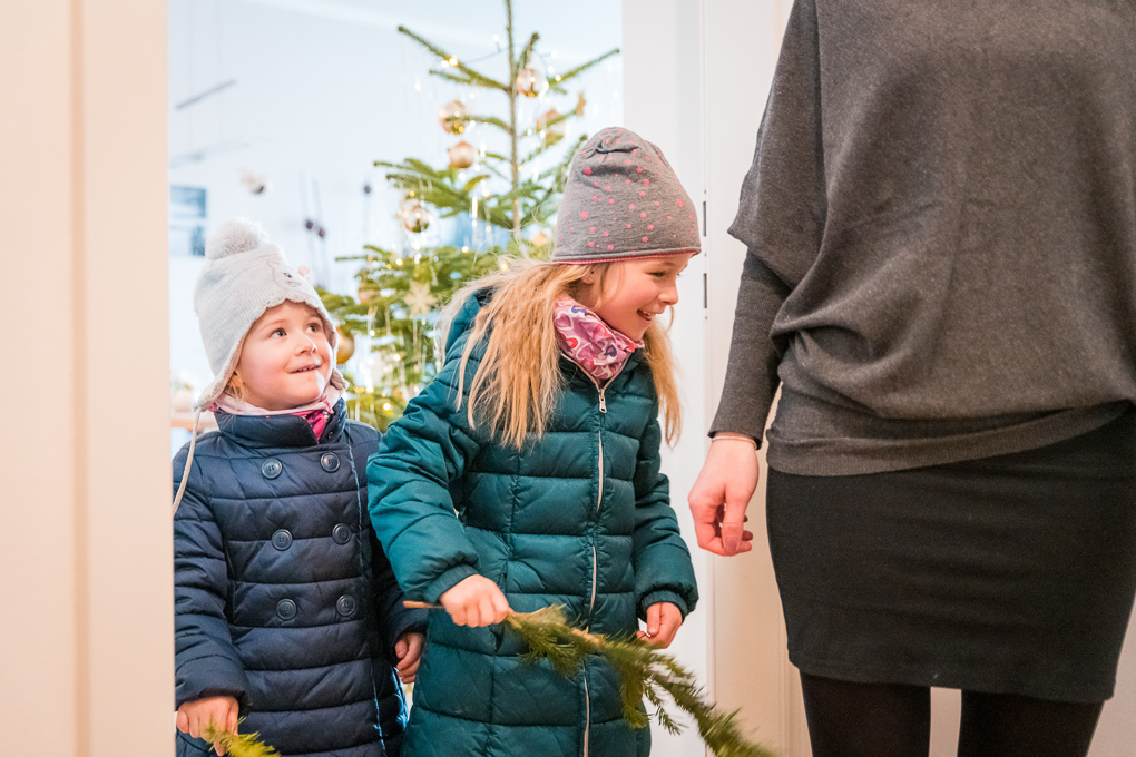 zwei Kinder in Wintermänteln und Hauben mit Zweig in der Hand am "unschuldige Kindertag", der zu den Bräuchen im Advent und in der Vorweihnachtszeit zählt