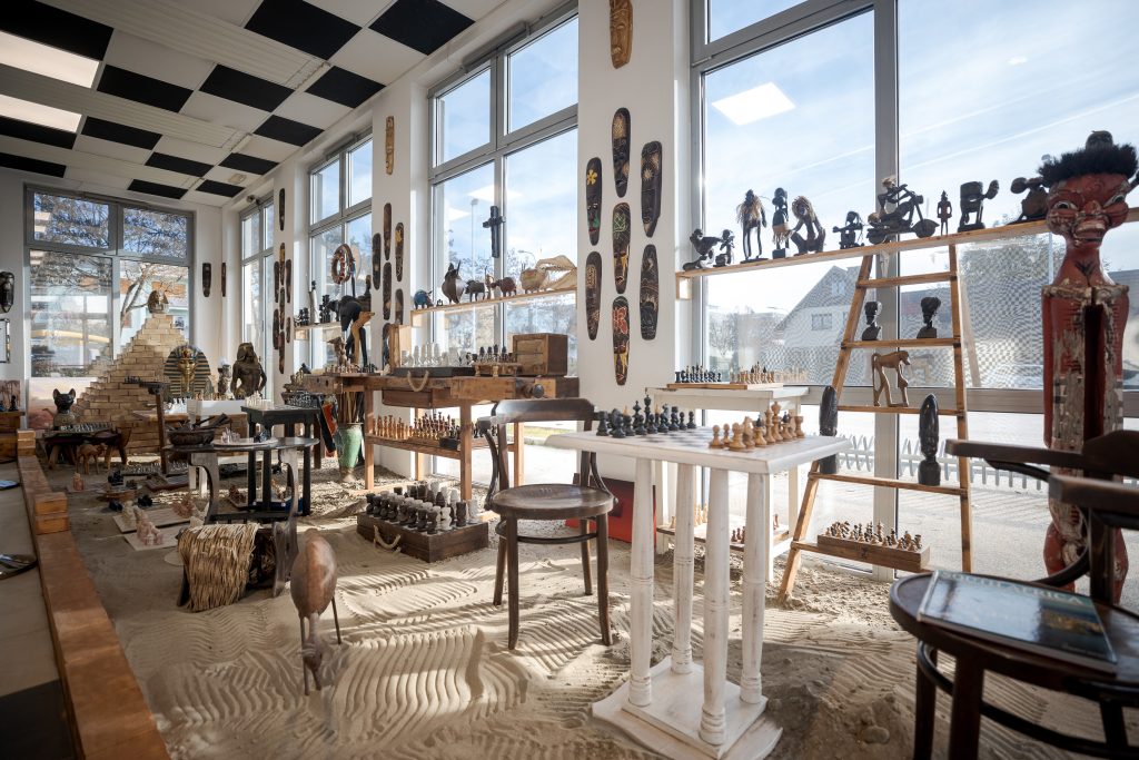 Blick in die fensterverglaste Ausstellungsfläche des neuen Schachmuseums in Klagenfurt mit vielen unterschiedlichen Schachspielen
