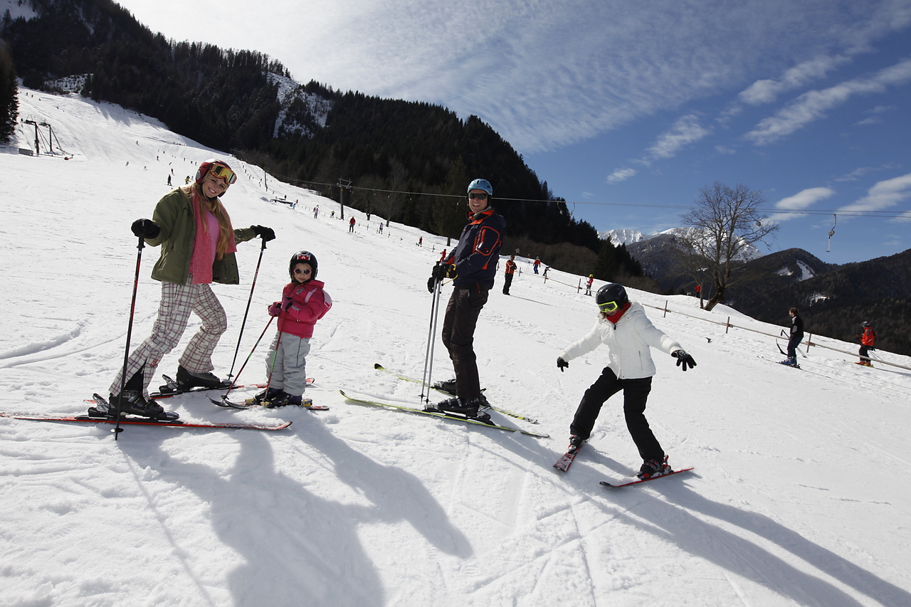 Eine Familie  - Elter mit zwei Kindern - stehen in Skiern auf der Piste im Bodental und lächeln in die Kamera