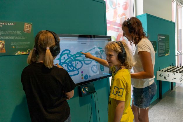Hands-On.Station im Mitmach-Museum Wissenswertwelt in Klagenfurt mit drei Kindern, die vor einem Bildschirm stehen