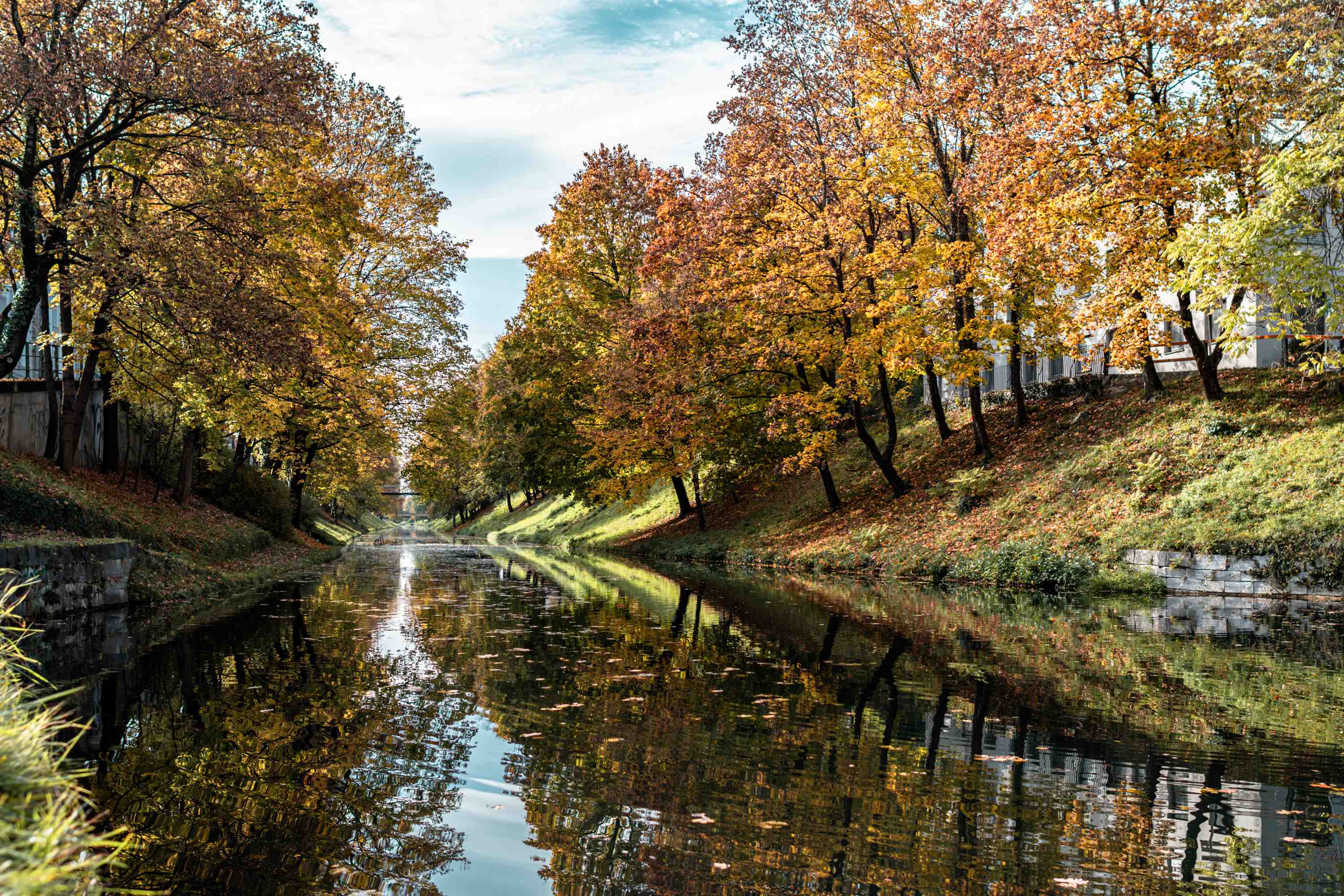 Blick auf den von bunten Herbstlaubbäumen gesäumten Lendkanal in Klagenfurt