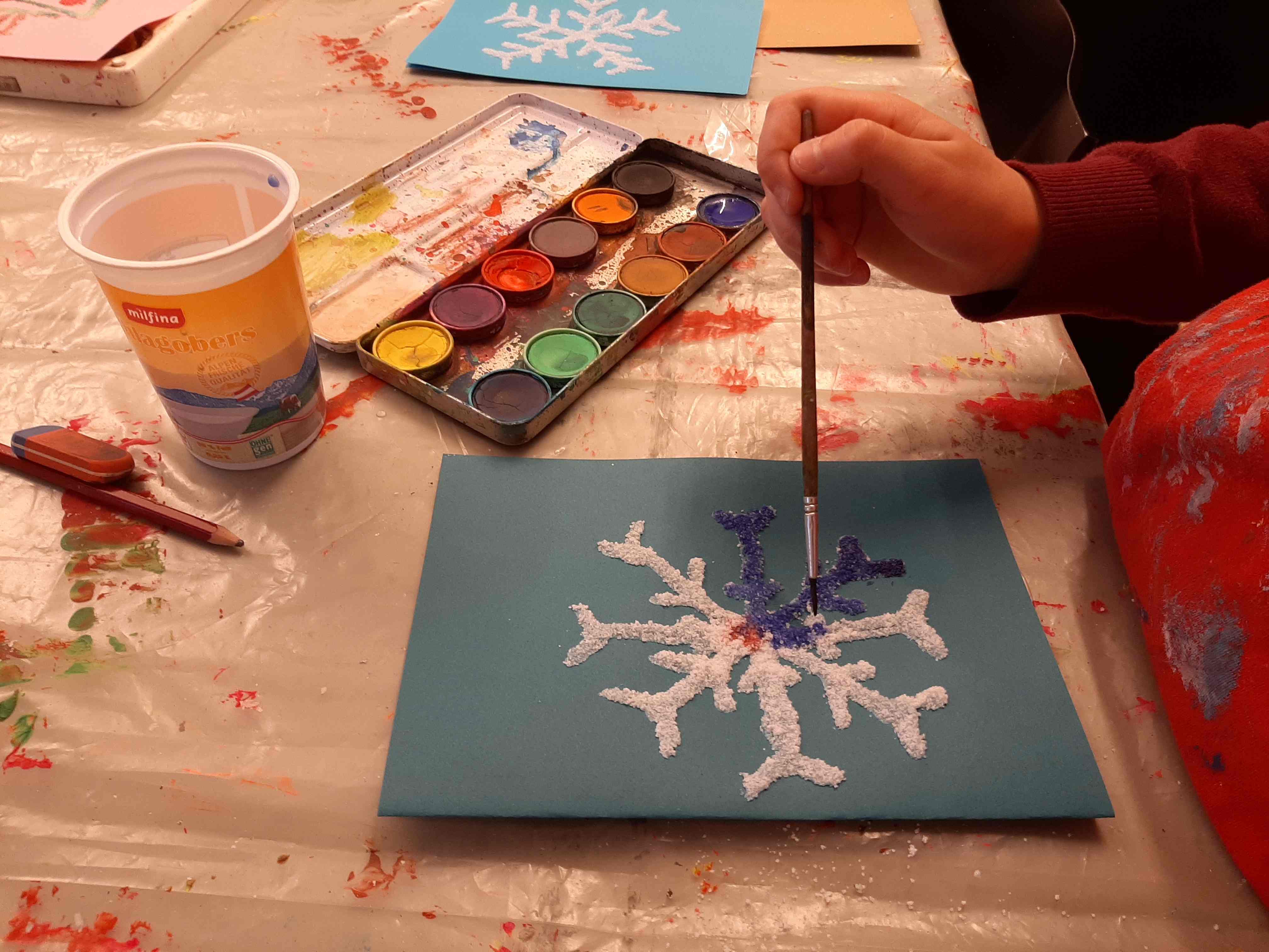 Workshop Weihnachtsatelier: Kind malt eine Glitzer-Schneeflocke im MMKK