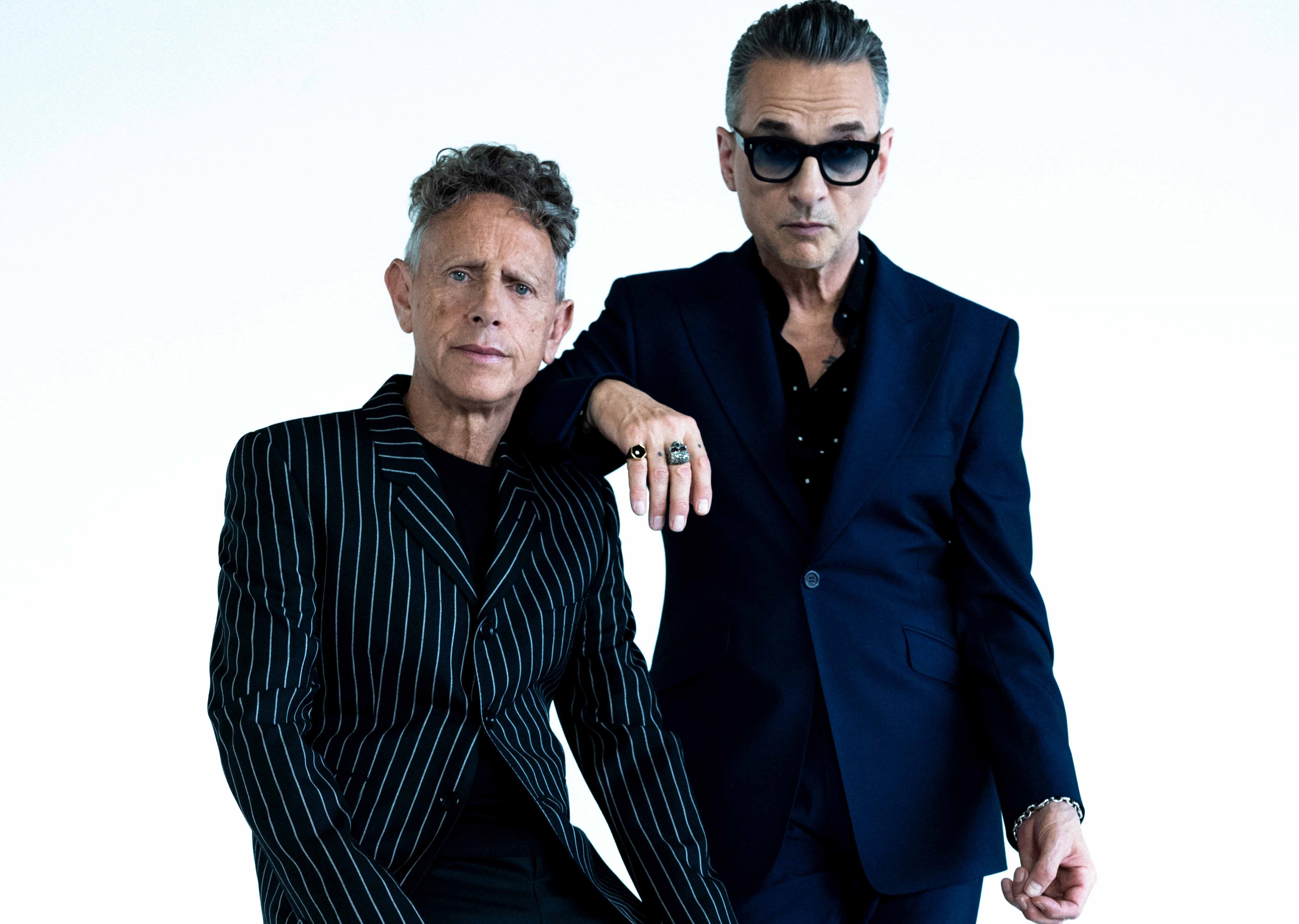Die Musiker von Depeche Mode in dunklen Anzügen vor weißem Hintergrund