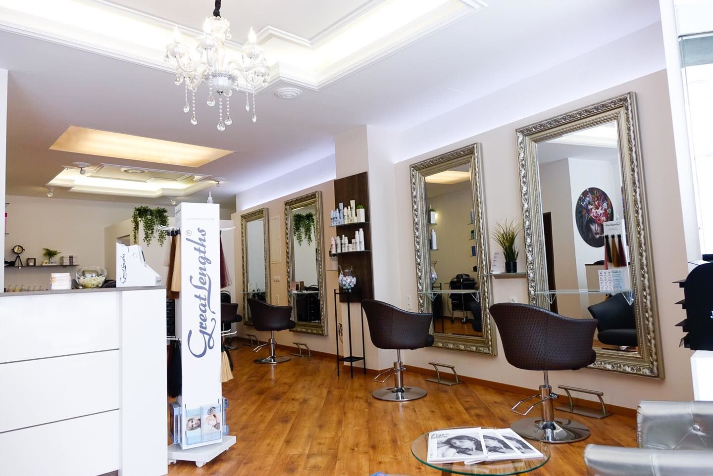 Blick in den hellen Raum von Emiras Salon mit dem Empfangstresen links und rechts Schneideplätzen mit Spiegeln
