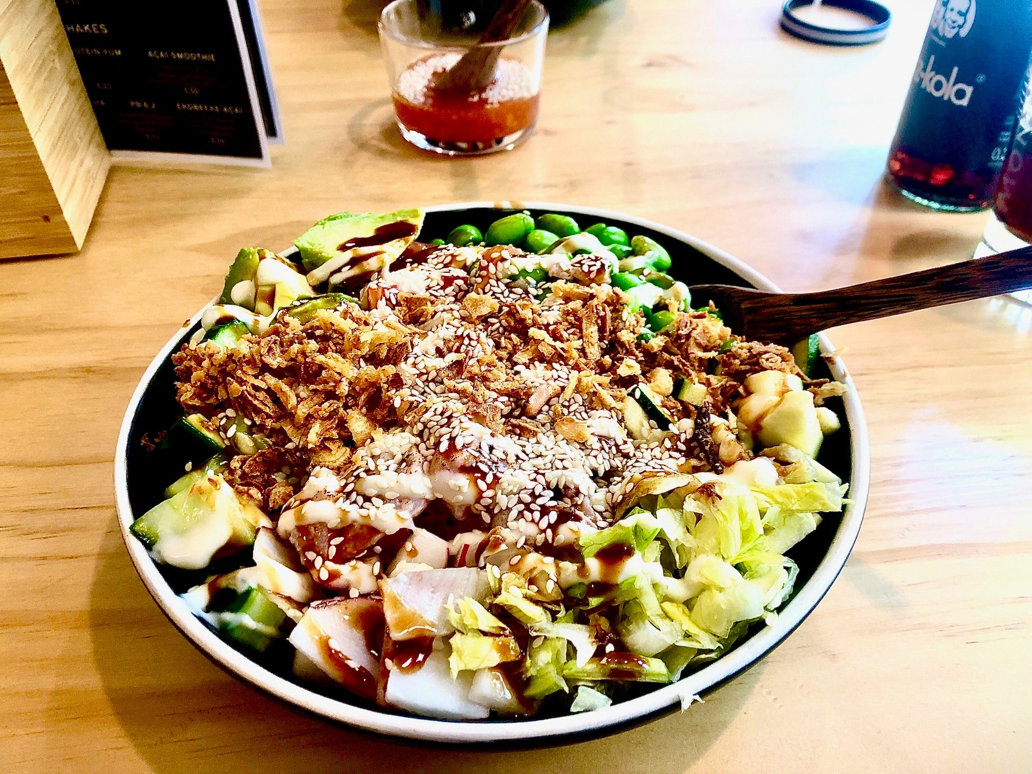 Eine Surf Side Bowl mit Salat, Avocados, Bohnen und heimischem Fisch auf einem Holztisch
