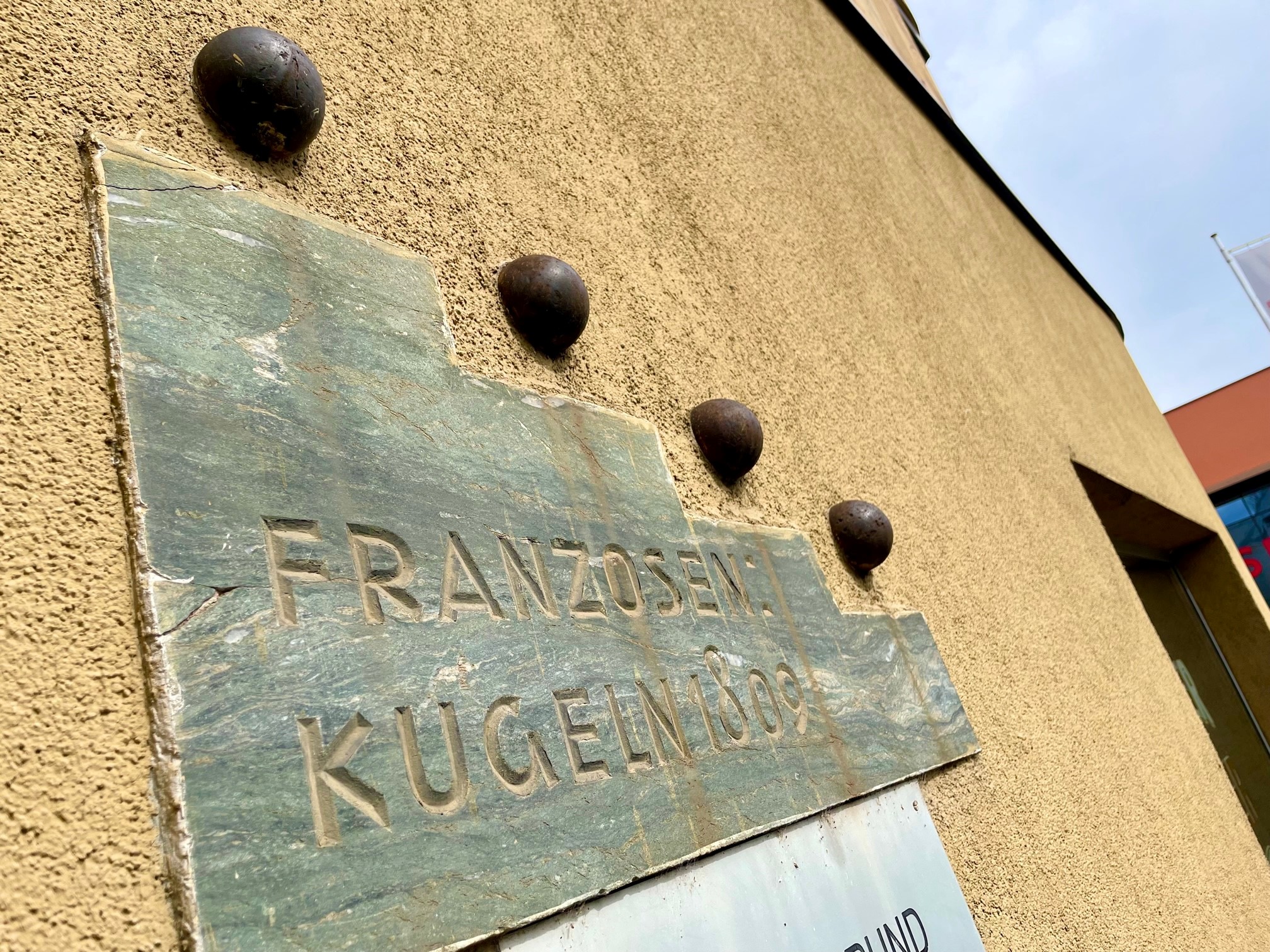 Hausfassade St. Veiter Straße Ecke Heuplatz, in der laut Inschrift vier Franzosenkugeln aus 1809 stecken