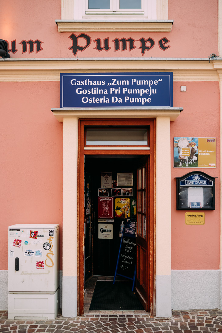 Eingang zum Gasthaus Pumpe in Klagenfurt mit blauem Schild über der Tür