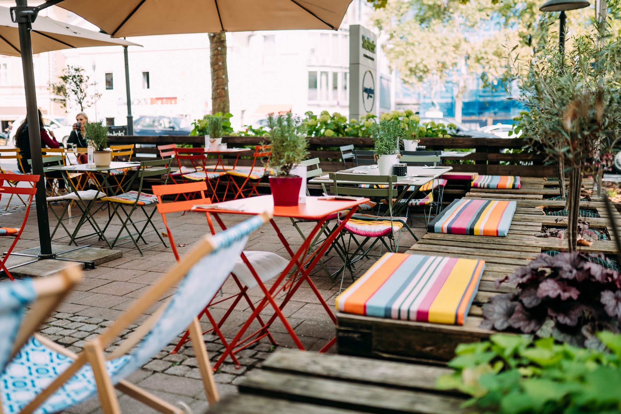 bunte Tische und Stühle im Gastgarten von Magdas Lokal in Klagenfurt