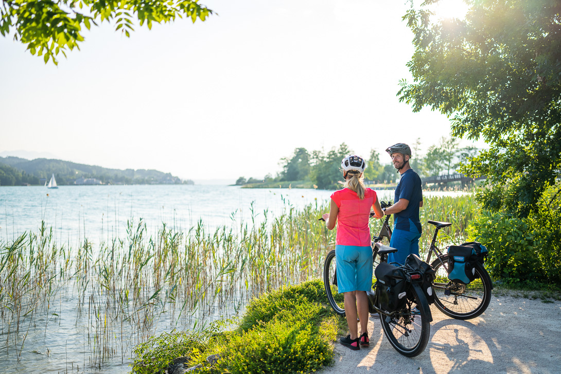 Paar macht Pause während Radtour und blickt auf den Wörthersee