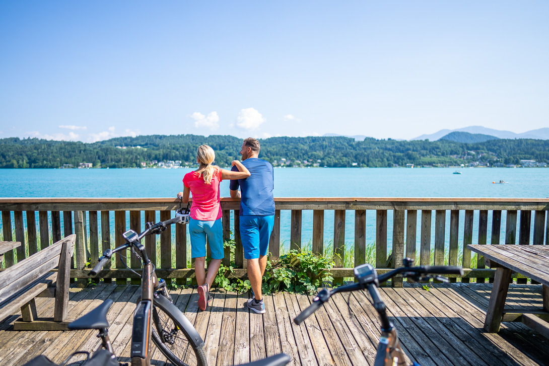 Paar macht Pause beim Radfahren und blickt auf den Wörthersee