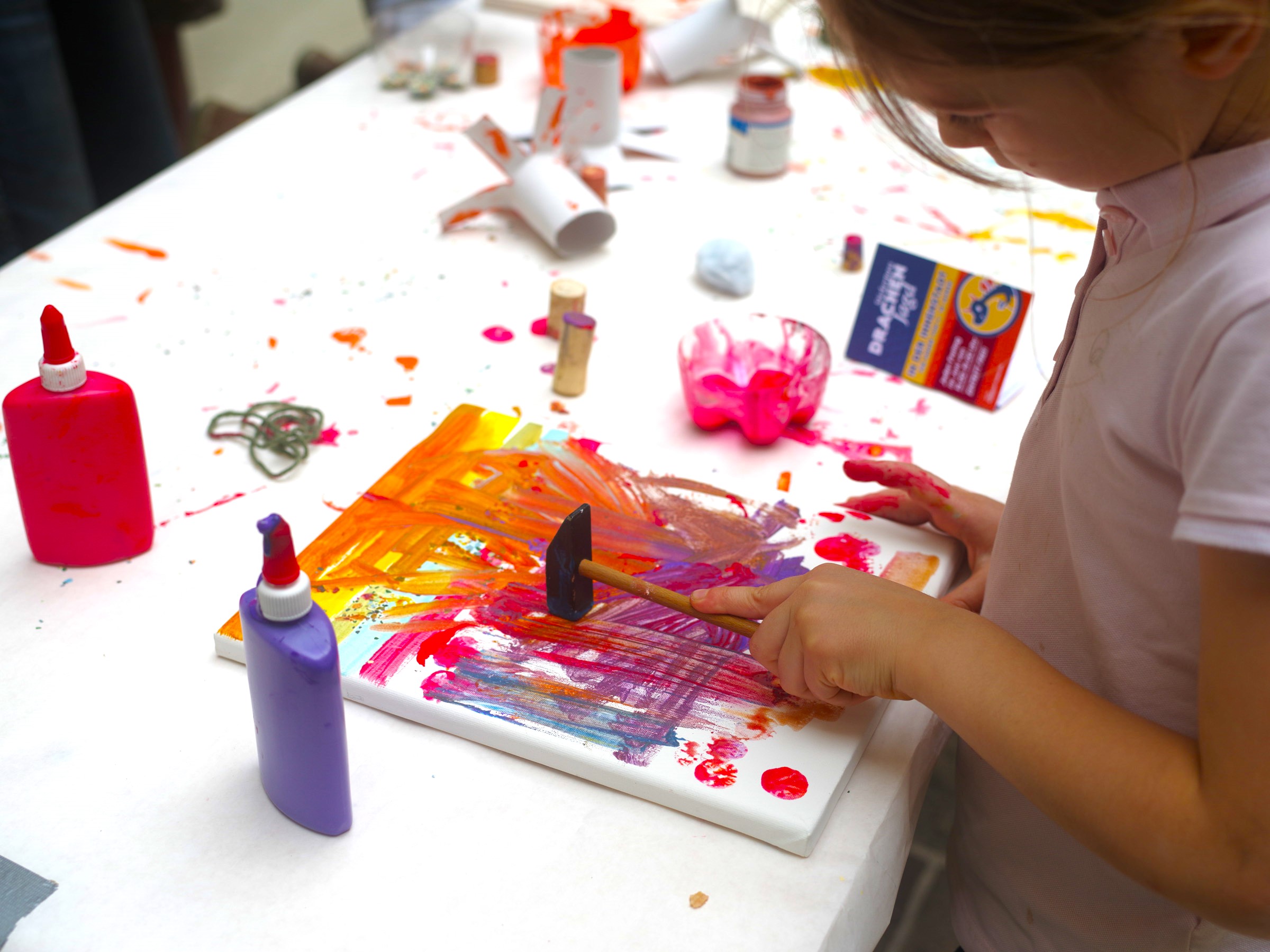 Kind malt mit Acrylfarben ein Bild im Rahmen der Drachenjagd
