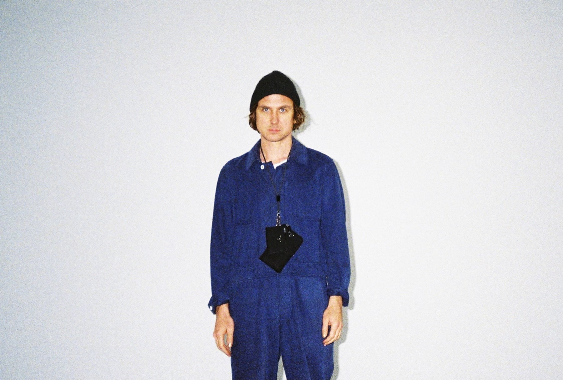 Portrait von Lars Eidinger in blauem Overall und mit schwarzer Haube