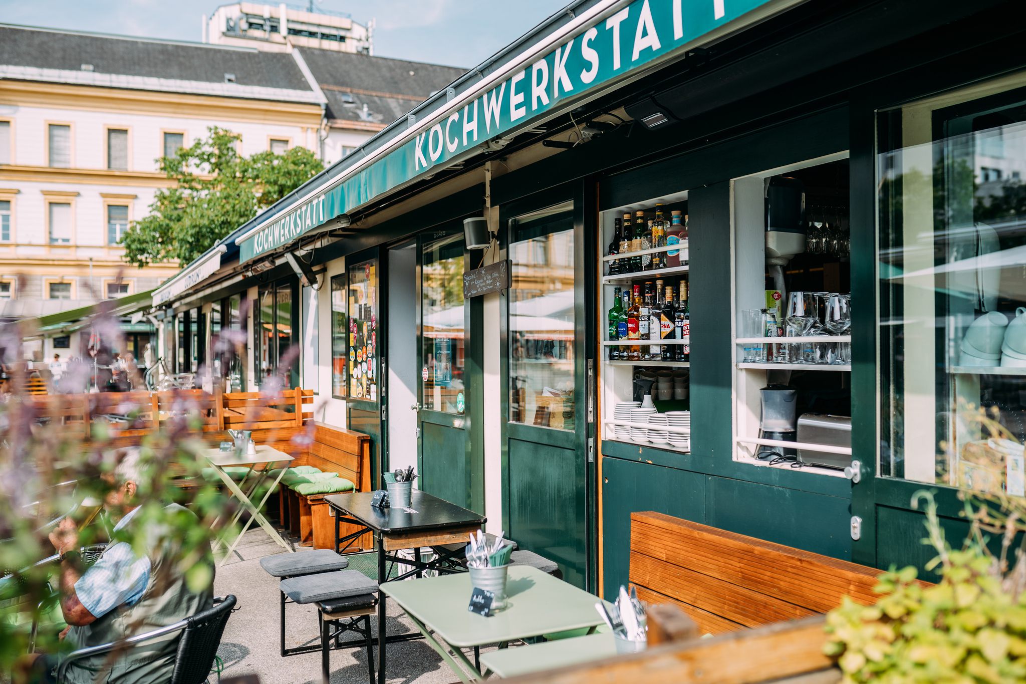 Gastgarten, Tische und Bänke in der Sonne vor der Kochwerkstatt klagenfurt