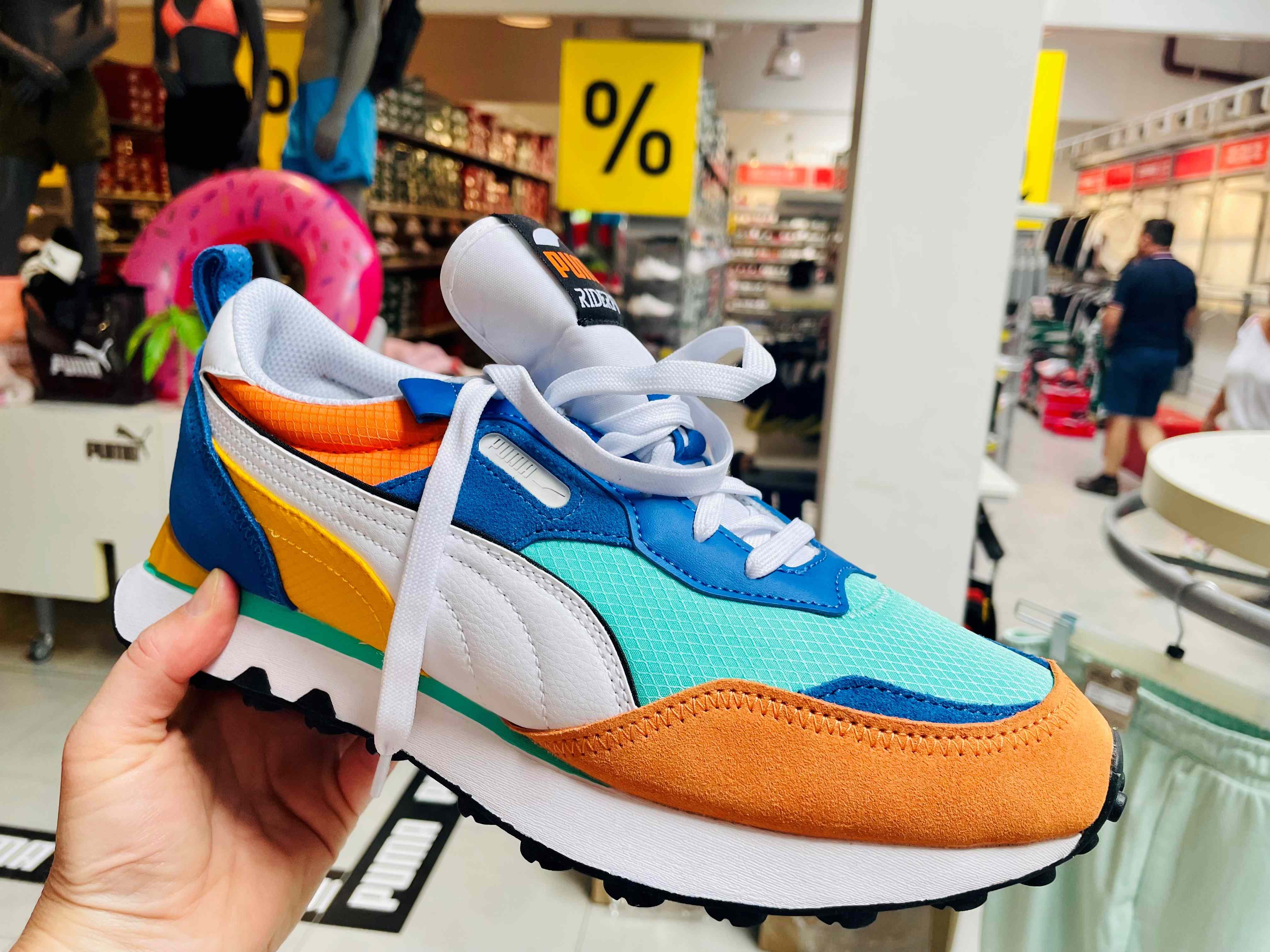 Puma-Sneaker im Vordergrund, Outlet-Store in Viktring im Hintergrund