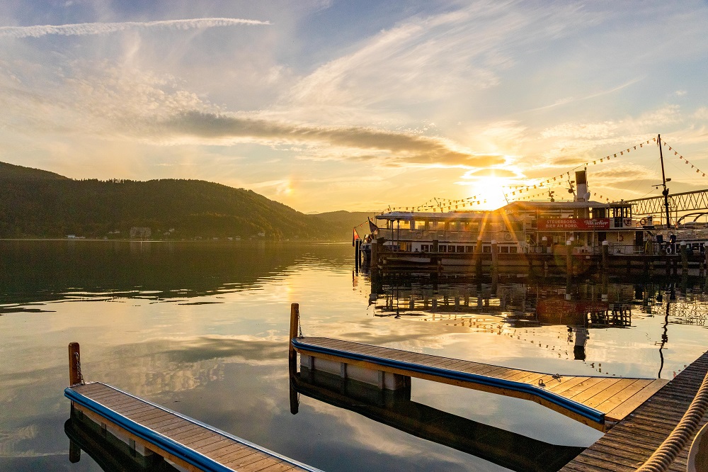 Blick von der Terrasse Villa Lido auf die Stege und das Seeufer bei Sonnenuntergang